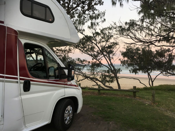 motorhome parked near some trees by the beach